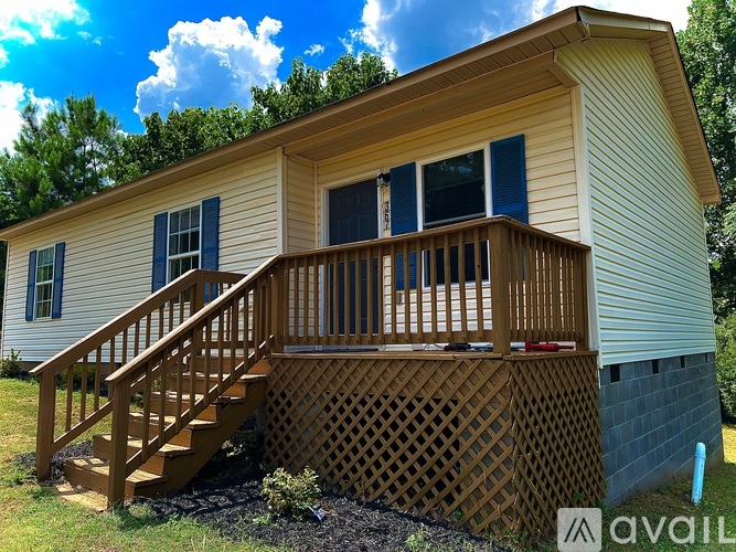A small house with a wooden deck and stairs leading to it.