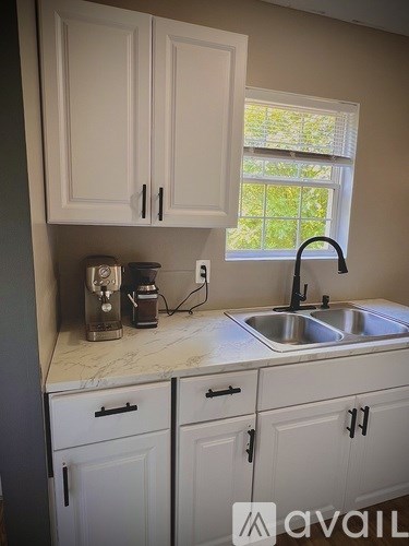 A kitchen with white cabinets and a marble countertop.