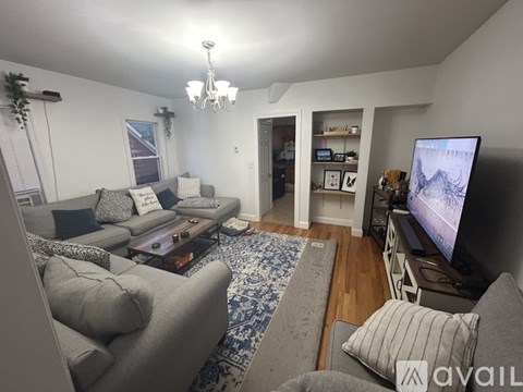 A living room with a grey couch and a chandelier.