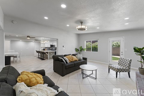 A living room with a black couch and a yellow pillow.