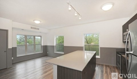 A modern kitchen with a large island and a refrigerator on the right side.