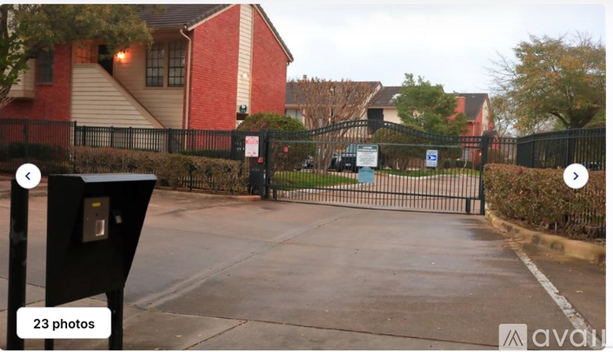 A black mailbox is on the left side of a street with a red brick house in the background.