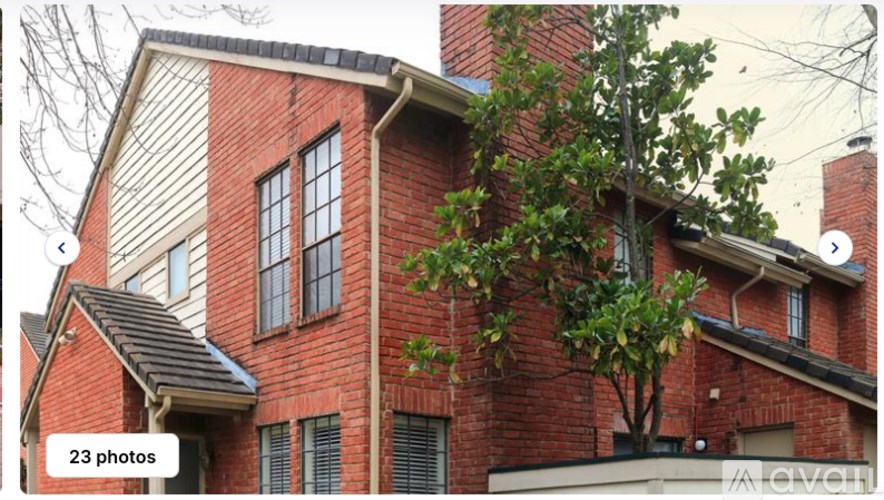 A red brick house with a tree in front.