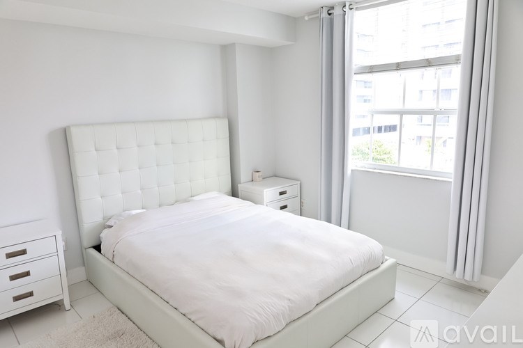 A white bedroom with a large bed and a window.