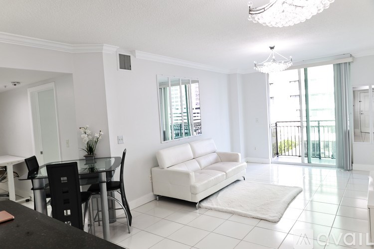 A living room with a white couch and a glass table.
