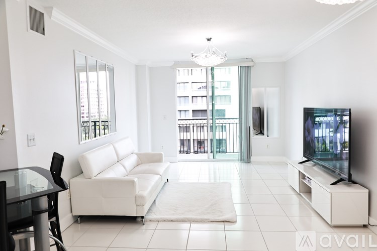 A living room with a white couch and a television on a white stand.