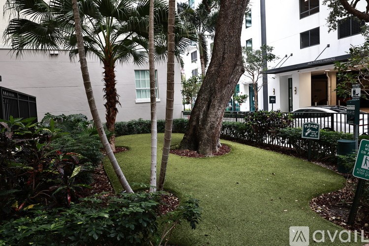 A well-maintained garden with a lawn, trees, and a sign in the background.