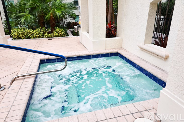 A hot tub with a blue border is surrounded by a tiled floor.