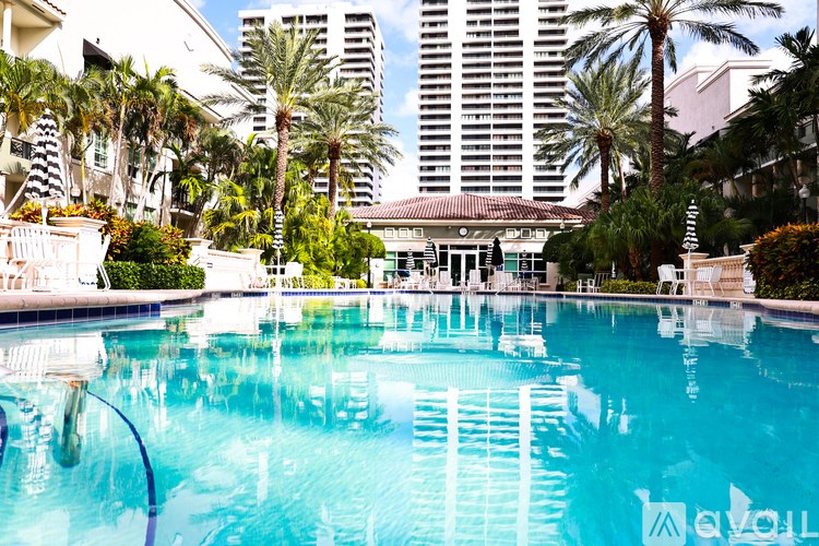 A large swimming pool surrounded by palm trees and buildings.