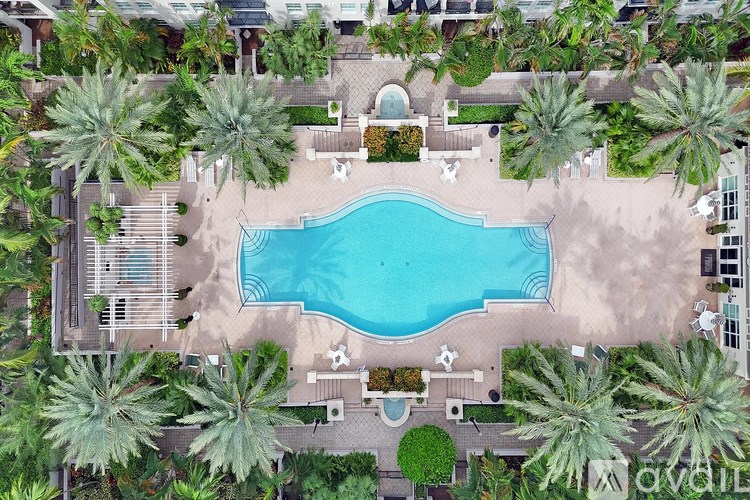 An aerial view of a pool surrounded by palm trees and lounge chairs.