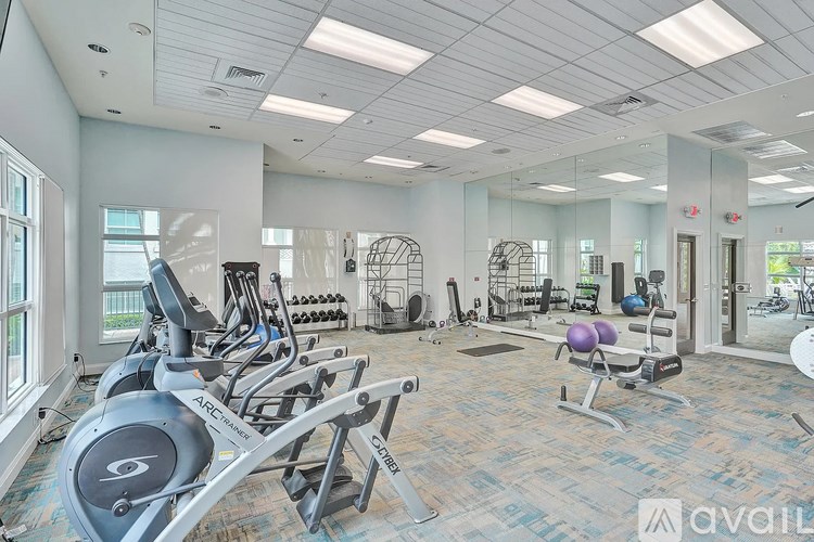 A gym with a variety of equipment including treadmills, weights, and exercise balls.