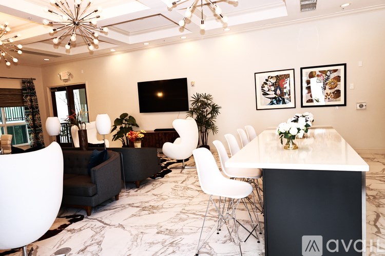 A living room with a white table and chairs, a black couch, and a television on the wall.