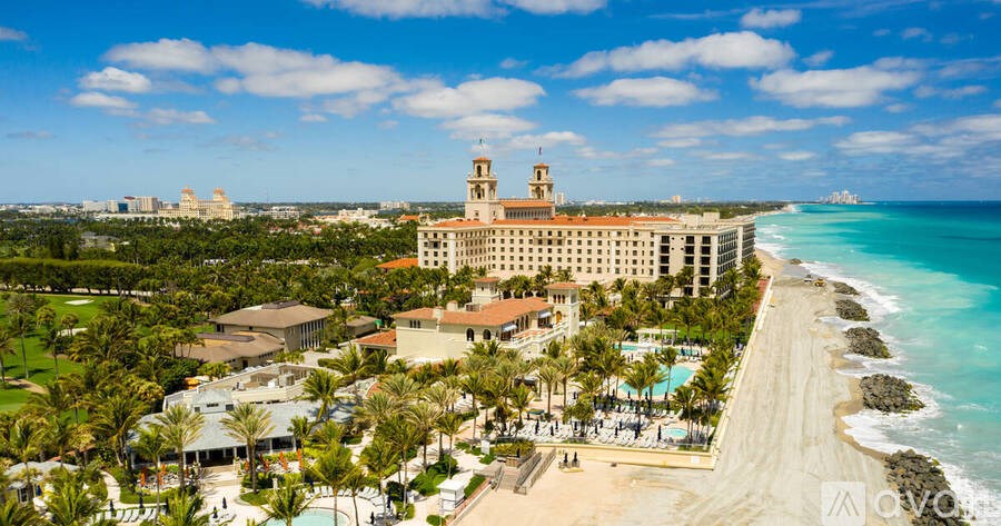 A large hotel complex with a beachfront and a tower in the background.