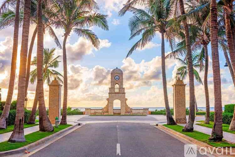 A beautiful archway surrounded by palm trees under a cloudy sky.