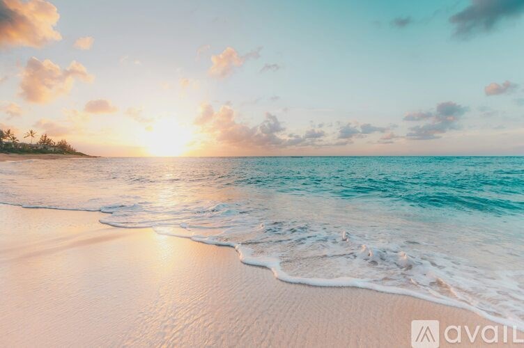 A beautiful beach scene with the sun setting over the ocean.
