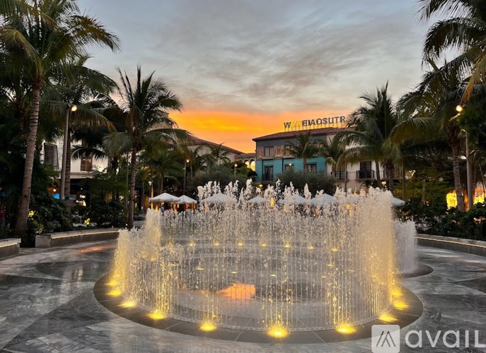 A fountain in the middle of a plaza surrounded by palm trees.