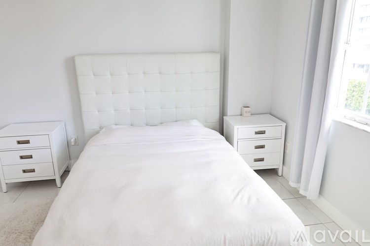 A white bedroom with a large bed and two nightstands.