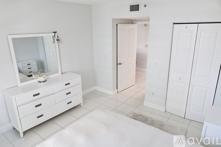 A white dresser with a mirror and a white rug in a room.
