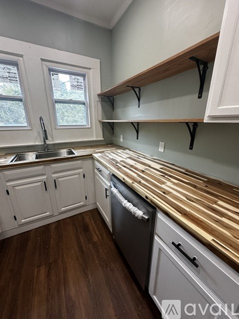 A kitchen with white cabinets and a wooden countertop.