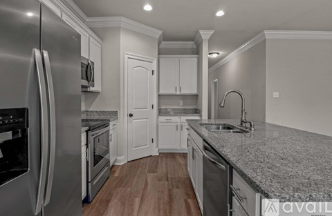 A modern kitchen with a stainless steel refrigerator and wooden flooring.