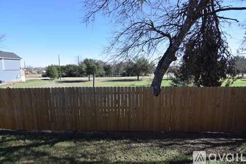 A wooden fence in a grassy area with a tree hanging over it.