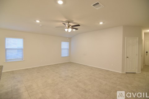 A spacious room with a ceiling fan and two windows.