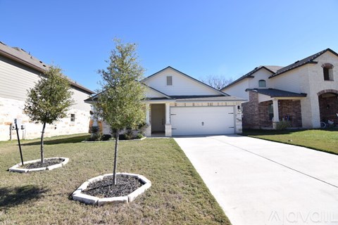A house with a white garage door and a tree in front of it.