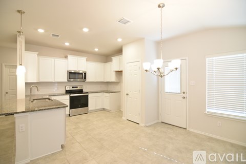 A kitchen with white cabinets and a granite countertop.