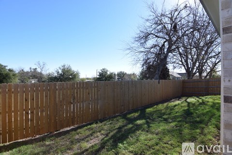 A wooden fence in a backyard with a clear blue sky.