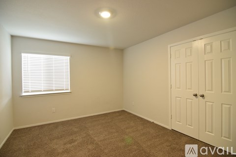 A room with a carpeted floor, a door, and a window with blinds.