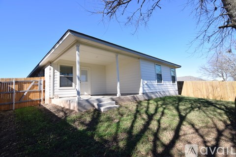 A house with a white front porch and a brown fence.