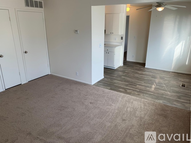 A room with a carpeted floor and a ceiling fan.