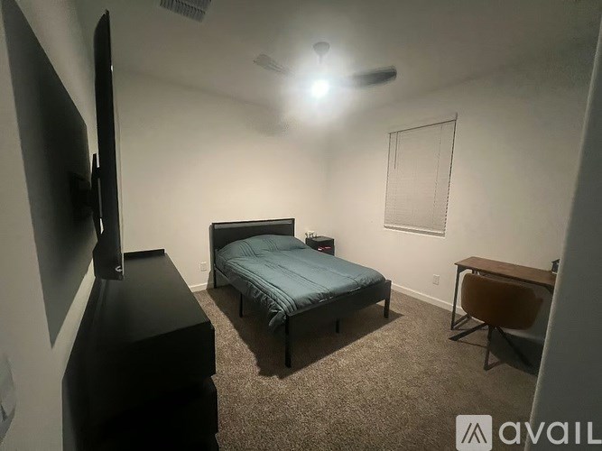 A bedroom with a bed, a television, and a chair.