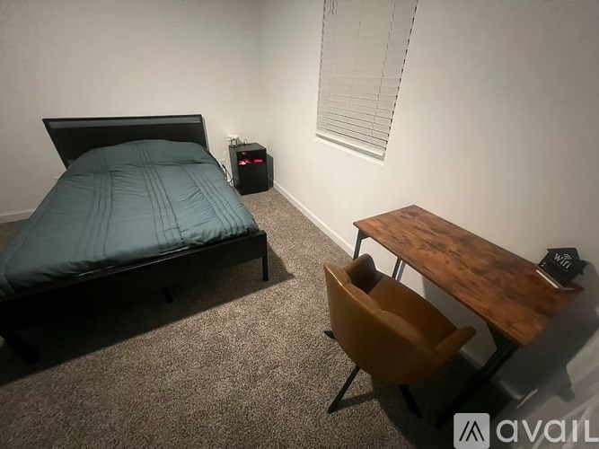 A bedroom with a bed, a desk, and a chair.