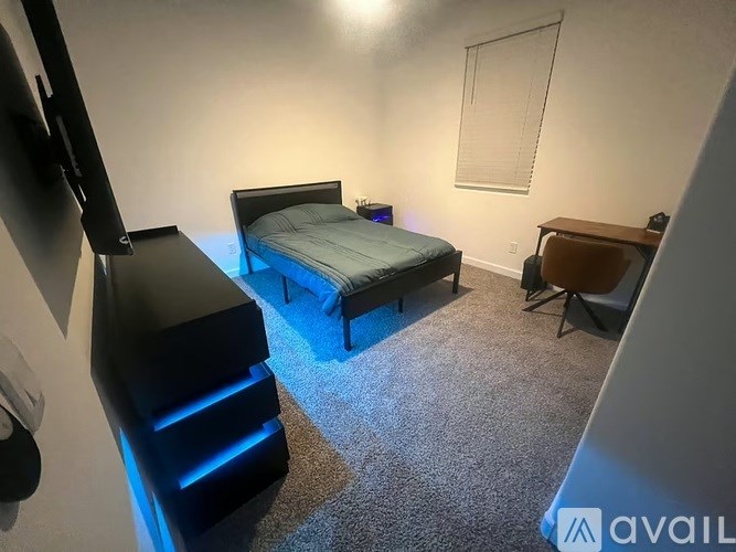 A bedroom with a bed, chair, and a television.