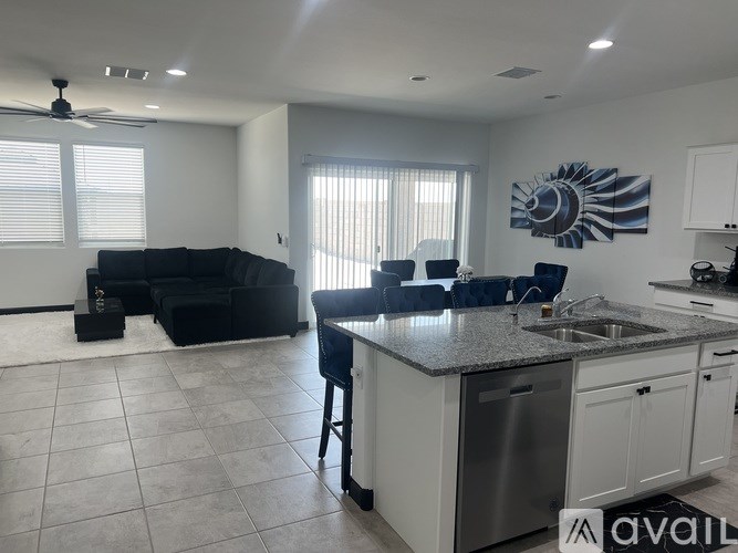 A kitchen with a black sofa and a ceiling fan.