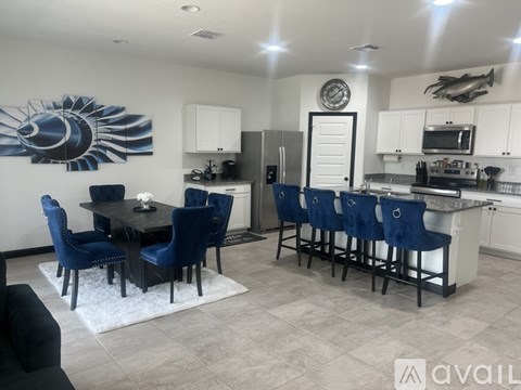 A modern kitchen with blue chairs and a dining table.