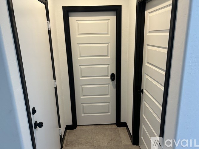 A white door with a black handle and a black frame is in the center of the image.