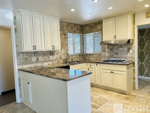 A kitchen with white cabinets and a granite countertop.