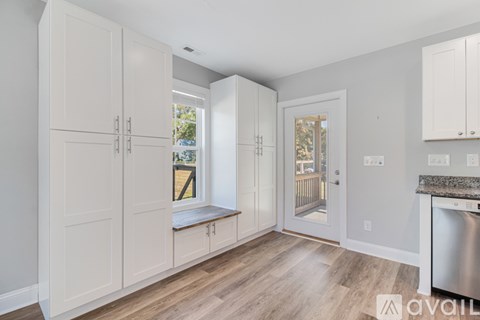 A kitchen with white cabinets and a wooden floor.