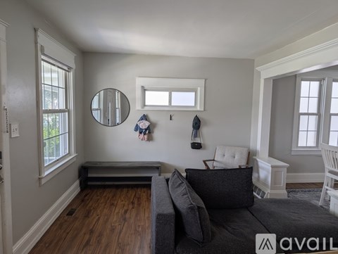 A living room with a grey couch and a round mirror on the wall.