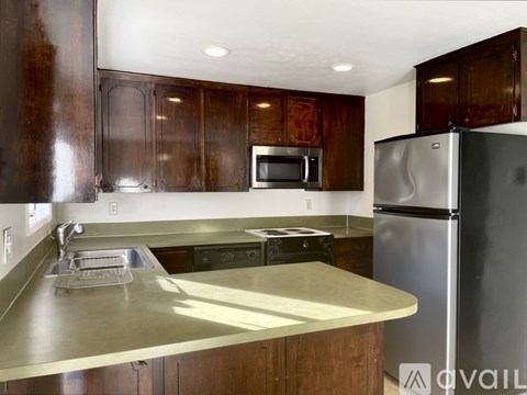 A kitchen with a stainless steel refrigerator and wooden cabinets.
