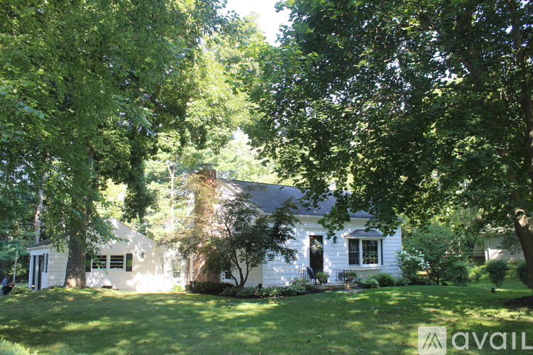 A white house with a black door is surrounded by trees.