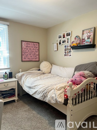 A bedroom with a white bed and a pink framed poster on the wall.