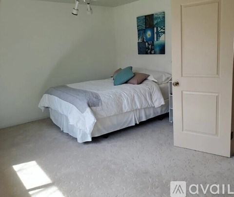 A bedroom with a white bed and a blue pillow.