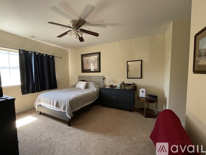 A bedroom with a bed, a dresser, and a ceiling fan.