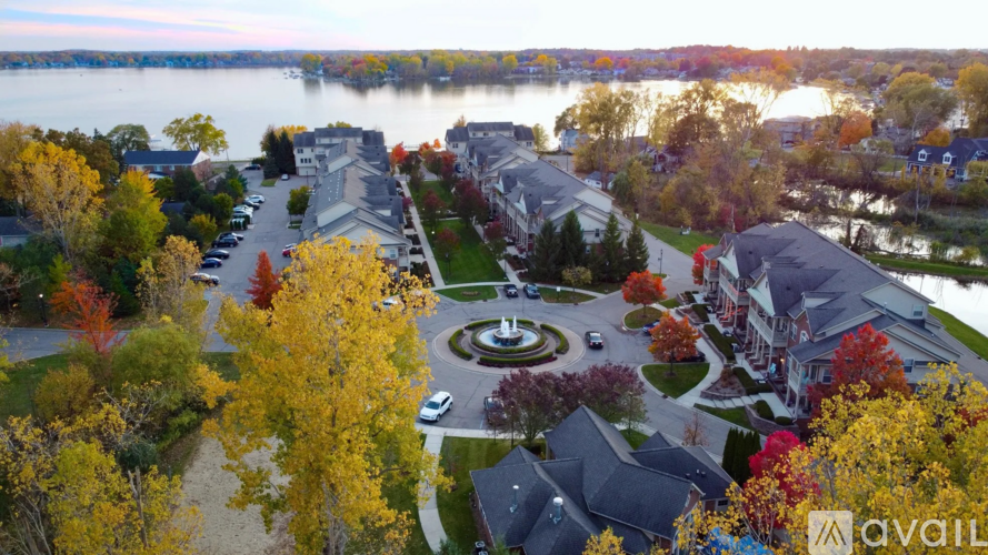 A bird's eye view of a residential area with houses, trees, and a lake.