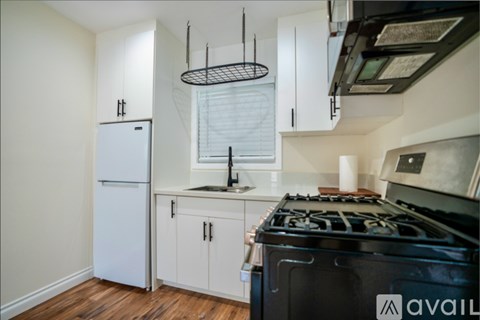 A kitchen with a black stove top oven and white cabinets.