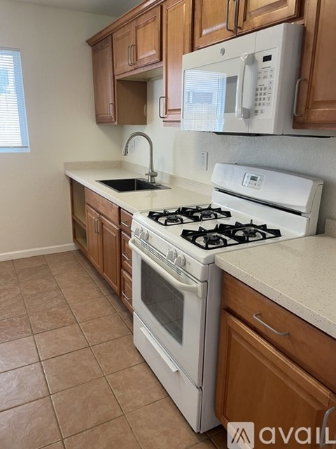 A kitchen with a white stove top oven and a white microwave above the counter.