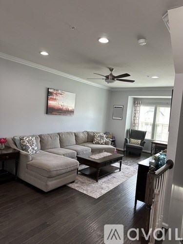 A living room with a grey sofa and a ceiling fan.
